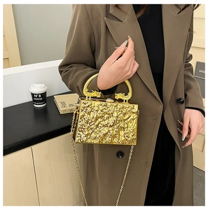 Detailed macro of golden acrylic clutch bag with ice-crack texture and dragon-shaped handle