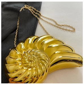 Detailed close-up of golden nautilus shell clutch with metallic texture and chain