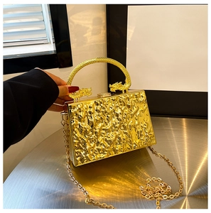 Detail of gold lava texture clutch with dragon-carved handle and metallic chain strap