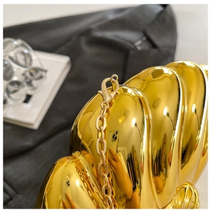 Macro detail of golden seashell evening clutch with mirror finish and metal chain
