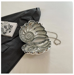 Detailed view of an open silver shell-shaped evening bag with metallic lining and chain