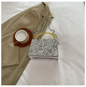 Silver ice-cracked acrylic box bag with gold circular handle and metal chain detail