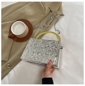 Detail of silver water ripple acrylic box bag with gold handle and metal chain
