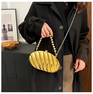 Detail of gold shell-shaped evening clutch featuring metallic pleats and beaded handle