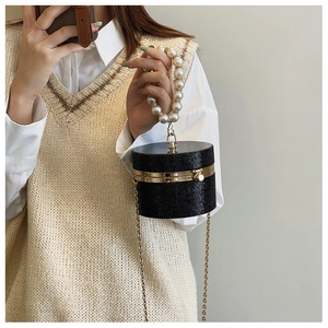 Close-up of black cylinder evening bag with sparkling diamonds and pearl handle