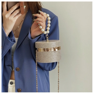 Detail of rhinestone cylindrical evening bag with large pearl handle and gold chain