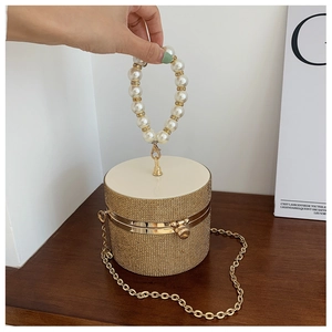 Detail of crystal cylindrical evening bag with pearl handle and gold chain strap