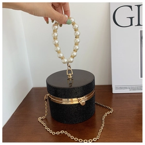 Detail of black rhinestone cylindrical evening bag with pearl handle and gold chain