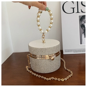 Detailed close-up of a luxury cylindrical evening bag with rhinestones and pearl handle