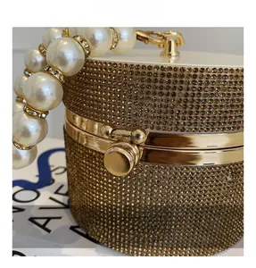 Close-up of golden rhinestone cylinder bag featuring a pearl handle and secure metal clasp