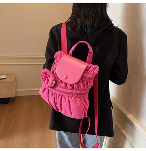 Détail d'un sac à dos plissé rose avec mini porte-monnaie assorti porté par un mannequin
