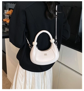 Vista dettagliata della borsa a mezzaluna bianca su un blazer nero con logo in metallo