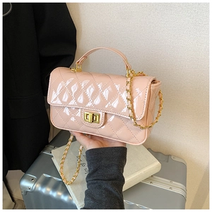 Detail view of pink quilted patent leather bag with gold clasp and metal chain strap