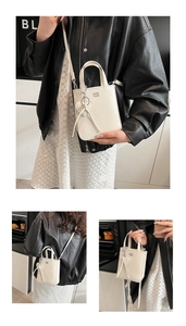 Detail of white leather mini crossbody bag with heart charm and brand logo engraving