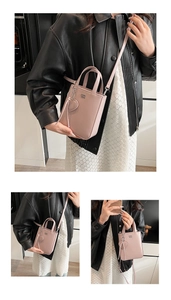 Detail of light pink mini handbag featuring lychee texture and heart-shaped pendant charm