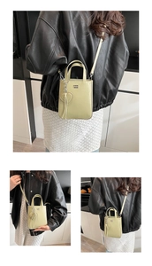 Detail of light green patent leather tote with heart charm and metallic logo hardware
