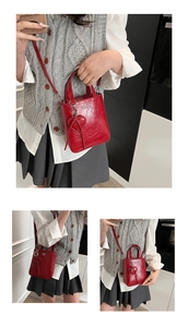 Detail of red glossy crossbody bag with heart pendant and metallic COIN ZBN logo