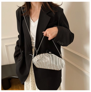 Detail of silver metallic evening clutch with 3D wave texture and glossy mirror finish