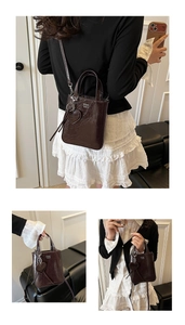 Detail of dark brown retro mini tote bag with glossy texture and heart-shaped pendant