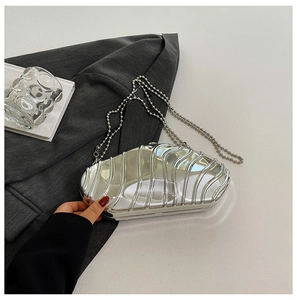 Detail of silver metallic evening clutch with 3D wave texture and chain strap