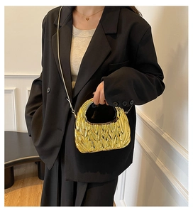 Close-up of golden metallic pleated crescent hobo bag with chain strap on black blazer