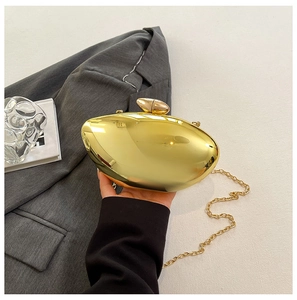 Detail of mirror gold bean-shaped evening clutch bag with pebbles clasp and chain