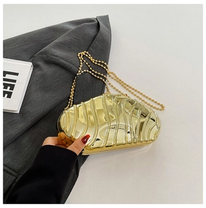 Close-up of golden wave-textured hard shell evening clutch with a sleek metal chain
