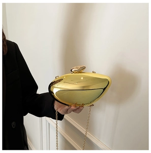Detail of a shiny gold shell-shaped evening clutch bag with chain held by a person