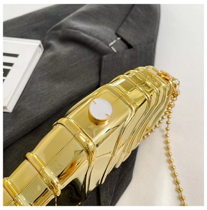 Detail of gold evening clutch featuring wave texture, metal finish and round clasp closure