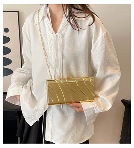 Detail of gold metallic evening clutch showing pleated texture and elegant chain strap