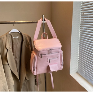 Detailed view of pink multi-pocket faux leather backpack hanging on a metal rack