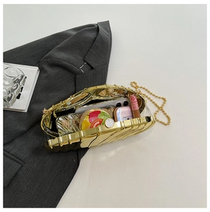 Detail of gold shell acrylic evening bag showing storage space with chain strap