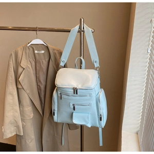 Detailed view of mint green faux leather backpack with multiple pockets on a stand