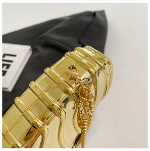 Macro view of golden hardshell clutch bag featuring textured wave patterns and bead chain