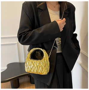 Detail of gold matelassé crescent handbag with metal chain strap and quilted texture