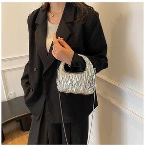 Close-up of a silver crescent clutch bag with metallic pleated texture and chain strap