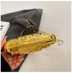 Detailed close-up of golden acrylic evening bag featuring luxury pleated wave texture