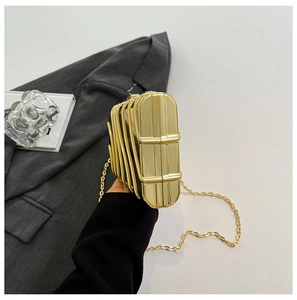 Detail of the golden geometric hollow frame and black luxury evening clutch with chain
