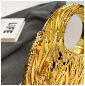 Detail of gold crescent evening bag with pleated texture and circular handle