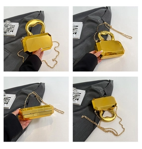 Detailweergaven van een gouden geometrische achthoekige clutch met handvat en ketting