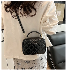 Détail du sac en cuir verni noir matelassé avec logo doré et finitions chic
