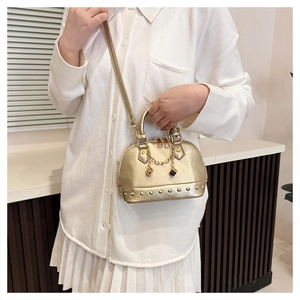 Golden shell bag detail with rivet studs, chain charm, and dice ornament in lifestyle setting