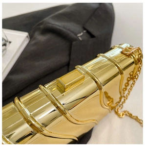 Close-up of golden evening clutch with wavy metal texture and fine chain strap