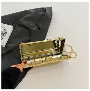 Detailed view of a gold evening clutch with bamboo texture and detachable chain strap