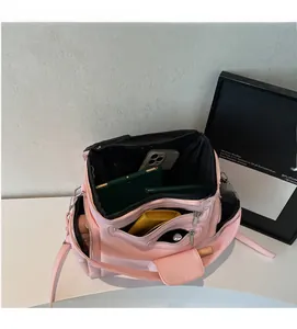 Detail view of pink nylon crossbody bag with multi-layer compartments and small coin purse