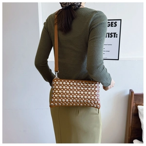 Detailed view of brown PU leather crossbody bag with silver round rivet decorations