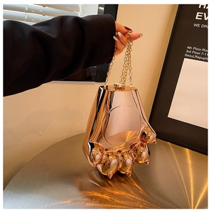 Dettaglio pochette a forma di zampa d'orso in oro rosa lucido con tracolla a catena d'oro