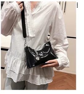 Détail du sac bandoulière en cuir ciré noir avec une grosse chaîne en métal argenté