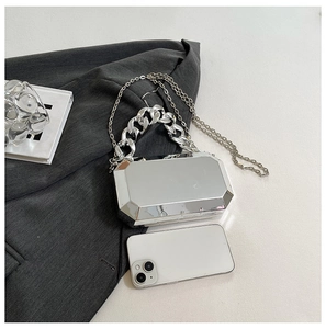 Detail van zilveren geometrische acryl clutch met grove ketting en telefoon voor maat