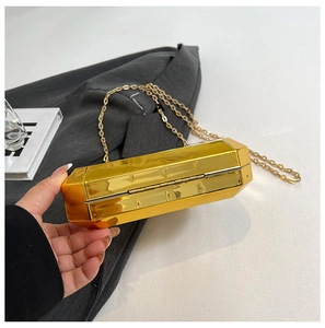 Detailweergave van een gouden geometrische clutch met een slanke metalen kettingriem